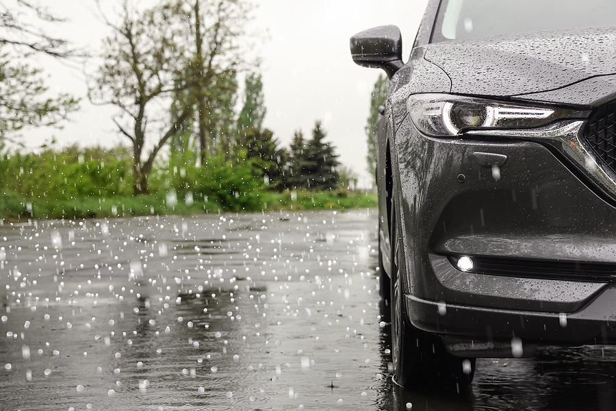 Modern car parked outdoors on rainy day with hail.